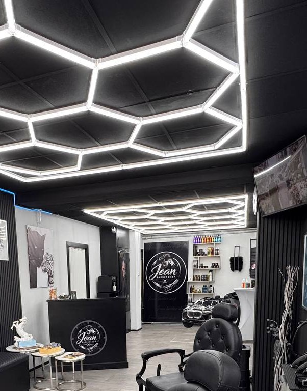 Het lichtplafond boven de balie met het logo van Jean Barbershop